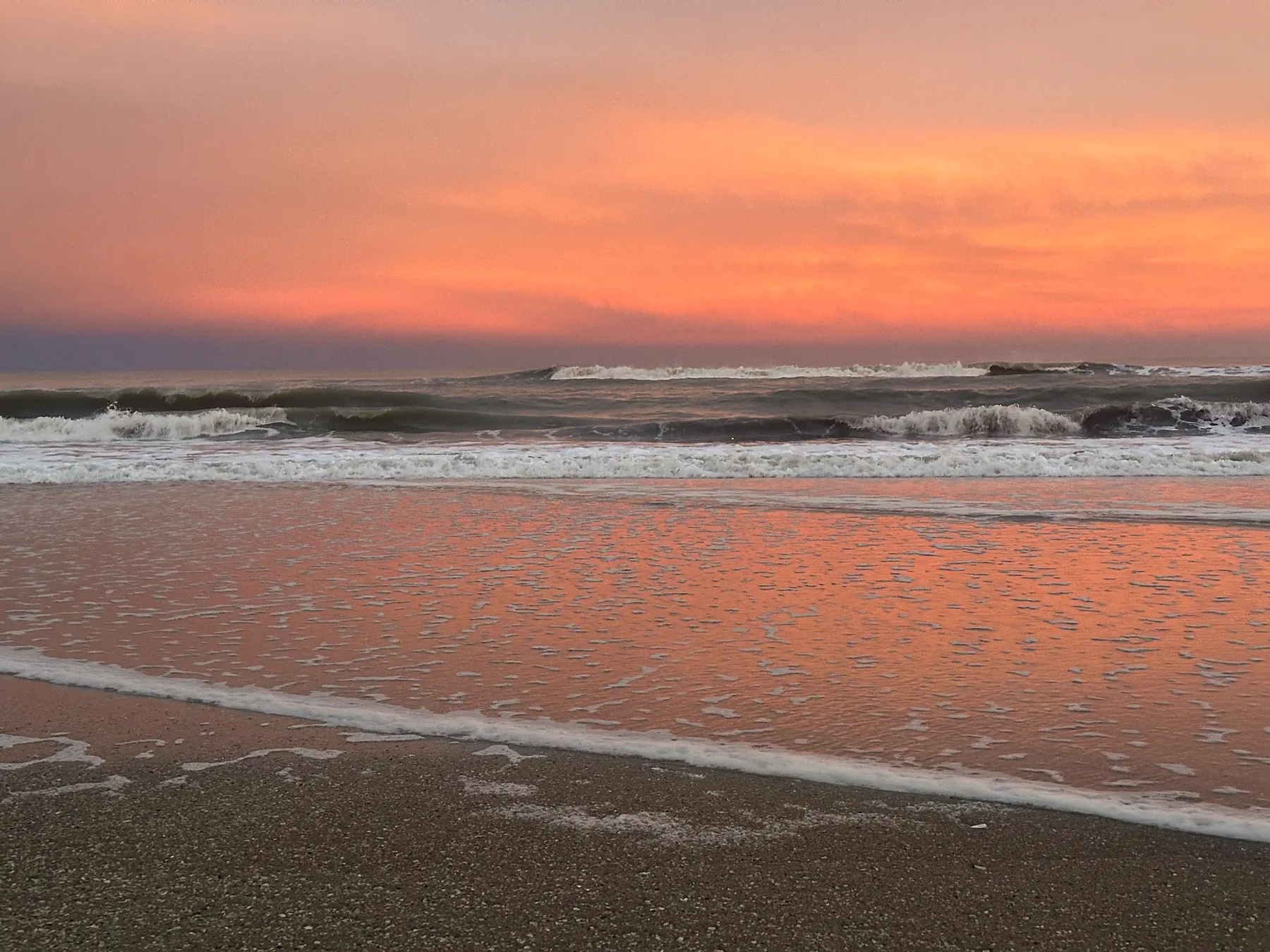 Atardecer naranja reflejado en la orilla