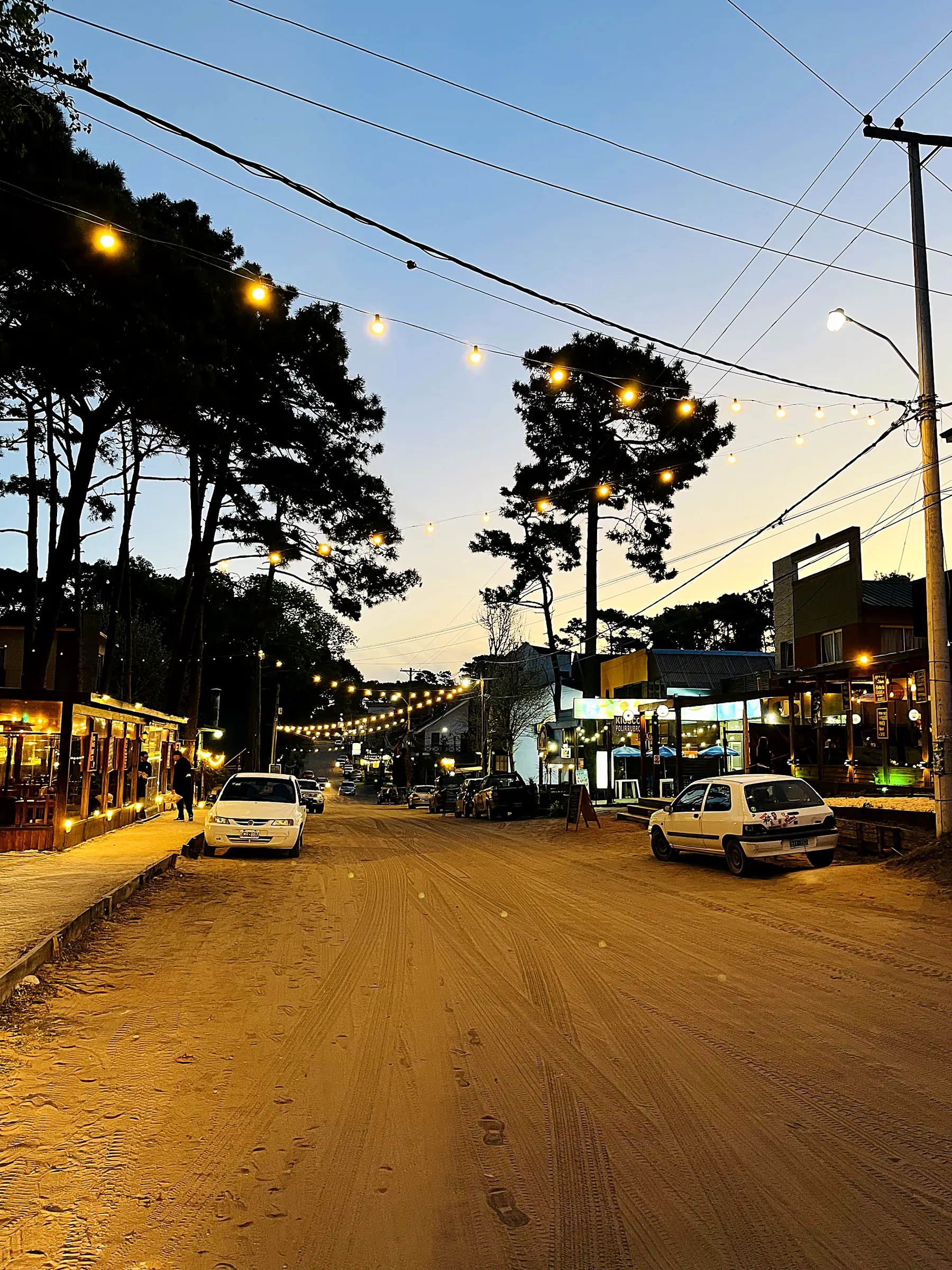 Calle de arena con comercios al caer la tarde