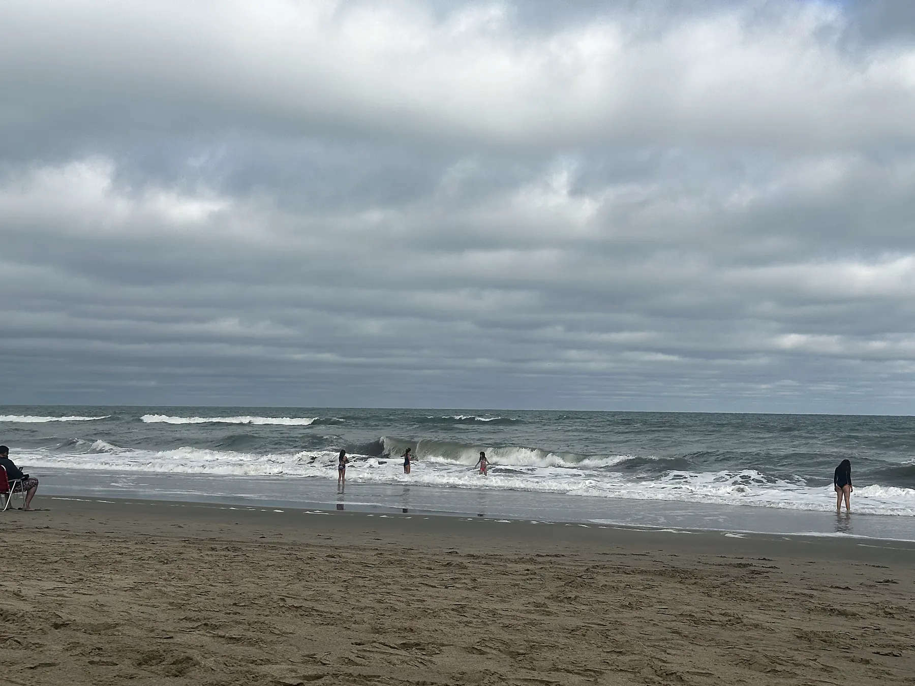 Playa ancha con el mar picado y el cielo cubierto